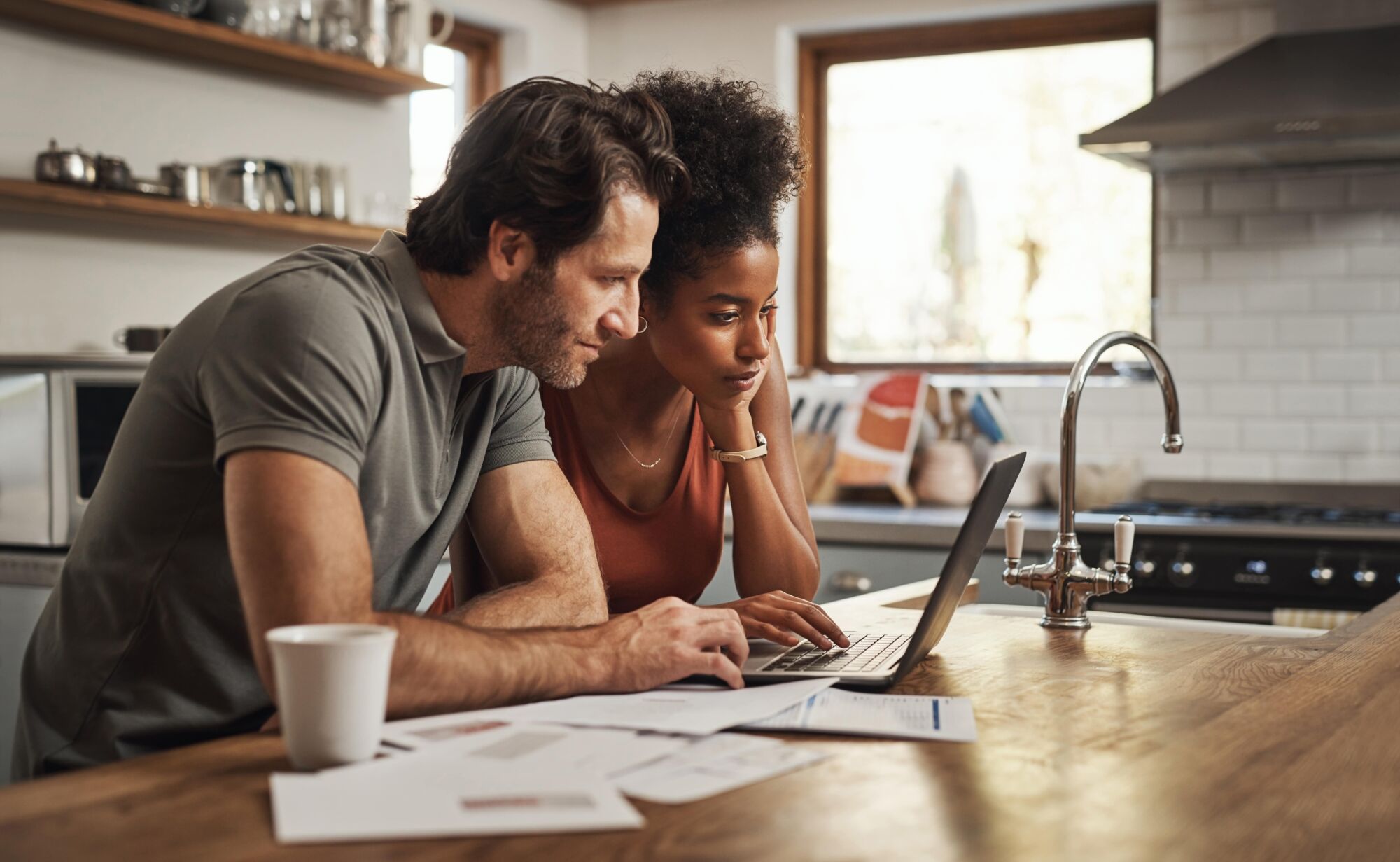 man and woman looking at a laptop on a kitchen counter