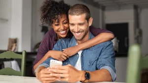 Happy man and woman looking at cell phone