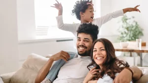 Mother, father and daughter sitting on the couch playing