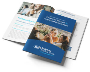 A booklet titled "Customer Impacts & Important Information" from Rollstone Bank & Trust rests on top of an open magazine displaying articles and images of smiling people.